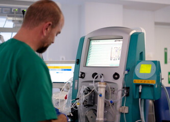 Doctor operating medical equipment for extracorporeal membrane oxygenation in hospital room