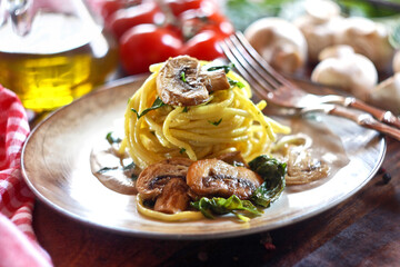 Spaghetti with mushroom and spinach on a wooden background