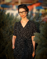 Young woman in dress and glasses in nature, casual style, outdoor portrait, natural light, relaxed...