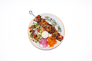Grilled chicken skewer with fresh mediterranean salad on white plate