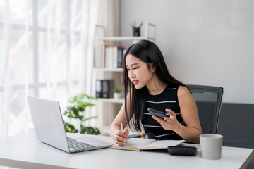 woman is sitting at a desk with a laptop and a calculator