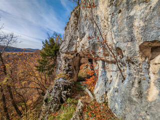 A view of the Háromkút Small Rock Arch from the opposite side, with vivid fall foliage and sculpted limestone cliffs in the Bükk Mountains.