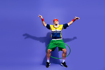 Elderly man hula hooping in colorful retro sportswear against a vibrant background showcasing...