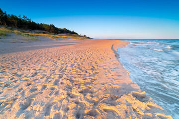 Beautiful waves crashing on the beach at sunrise, Polish sandy coast, Dąbki, Poland.