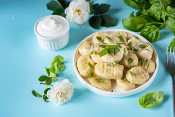 Potato dumplings on a white plate on a blue background. Gnocchi on a white plate for lunch. Close-up.