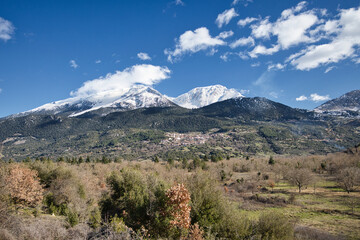 Fototapeta premium Snow-covered mountains rise quietly over rural Peloponnese 