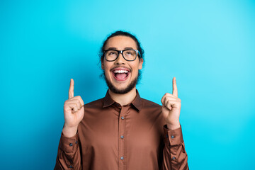 Cheerful Young Man Wearing Glasses Gesturing Excitedly Against Vibrant Blue Background in Stylish...