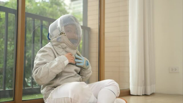 Before the tournament day, a boy dressed in fencing gear are rehearsing in gym