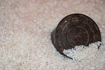 A measuring tin half buried in a pile of white rice
