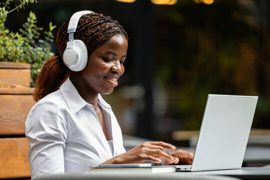 Elegant black African woman in business suit working on laptop computer in cafe bar.