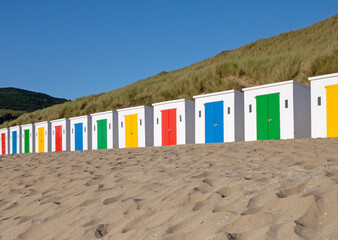Multi-colored beach huts on Woolacombe Beach resting on sand in North Devon, UK