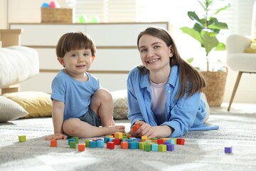Fototapeta premium Mother and son playing with colorful cubes at home
