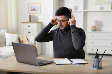 Naklejka premium Man learning online using laptop at desk indoors. Self-study