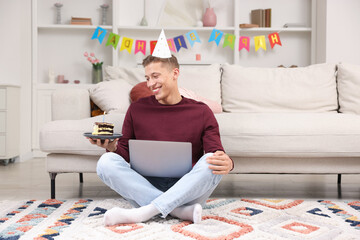Man with piece of cake celebrating his birthday and having video call via laptop at home