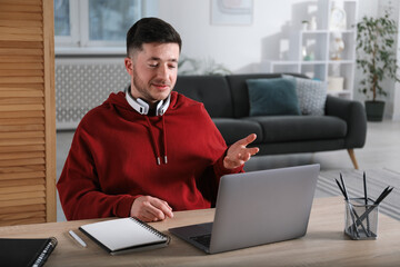 Man having online lesson with teacher via laptop at desk indoors