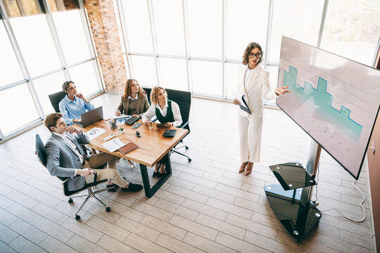 Professional business team collaborates in modern office during presentation showcasing data for corporate project success