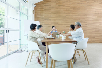 Group of elderly people discussing with female caregiver at a nursing home, reflecting social...