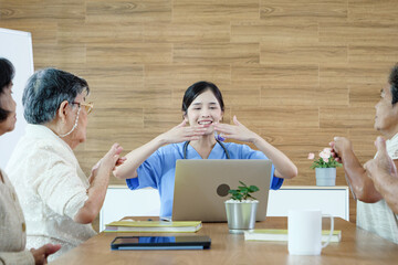 Group of elderly people discussing with female caregiver at a nursing home, reflecting social...