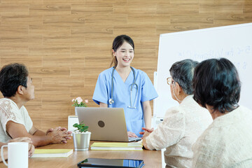 Group of elderly people discussing with female caregiver at a nursing home, reflecting social...