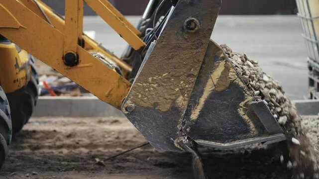 An excavator is vigorously scooping gravel soil at a busy worksite, showcasing various construction machinery in action