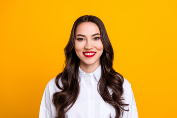 Fototapeta premium Portrait of a young cheerful woman in a white shirt, standing against a bright yellow background, exuding confidence