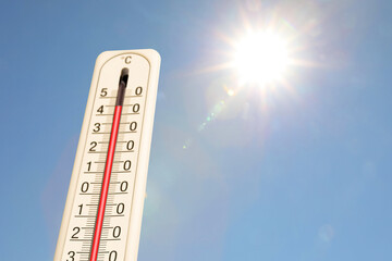 Extremely high temperature on thermometer against blue sky on sunny day. Summer weather