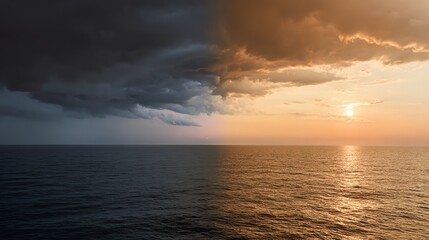 A dramatic seascape showing a sharp contrast between dark storm clouds and a golden sunset over calm ocean waters.