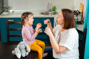 Cozy family interaction of woman playing with child in modern kitchen. Concept of preschool growth...