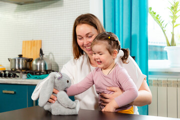 Happy woman encouraging childs motor skills with playtime in cozy kitchen. Concept of learning...