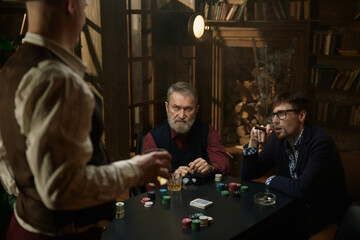 Three men enjoying tense poker game unfolds in a beautifully decorated vintage setting