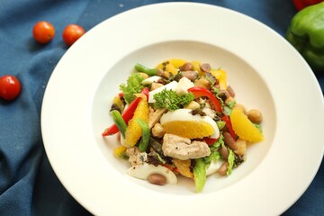 Fancy salad served on a white plate in a restaurant background