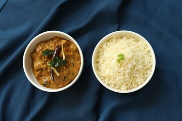 Indian food rice with curry or sabzi served in a white plate in a restaurant background 