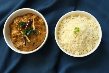 Indian food rice with curry or sabzi served in a white plate in a restaurant background 