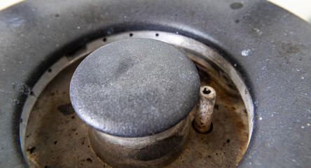 Close-up view of a gas hob burner with a round black cap and a visible igniter