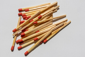 Scattered pile of wooden matches with red tips on a white background