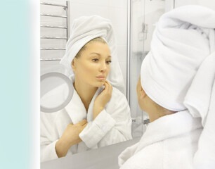 woman looking in the mirror in the bathroom and taking care of her skin.	