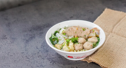 Savory Meatball Noodle Soup in White Bowl on Dark Concrete Background with Burlap