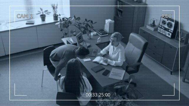 Security camera footage of biracial couple walking into modern counselling room then sitting at desk while visiting female doctor for family psychotherapy session