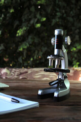 Concept of scientific experiments and education. There is a microscope on the table and part of a notebook with a pen for recording the experiment is visible