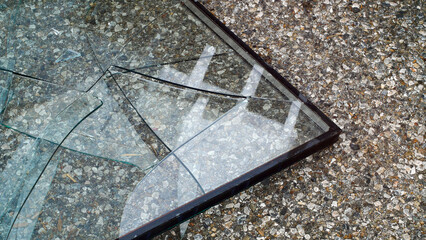 Broken glass with cracks lying on the asphalt close-up, aftermath of an accident, detailing