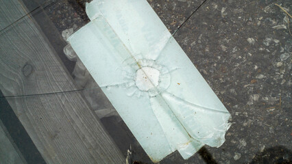 Broken glass with cracks lying on the asphalt close-up, aftermath of an accident, detailing