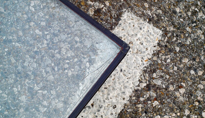 Broken glass with cracks lying on the asphalt close-up, aftermath of an accident, detailing