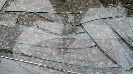 Broken glass with cracks lying on the asphalt close-up, aftermath of an accident, detailing