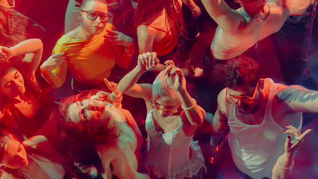 A vibrant crowd dancing energetically under colorful lights in a club atmosphere. Concept of nightlife party, youth, summer, festivity, celebration