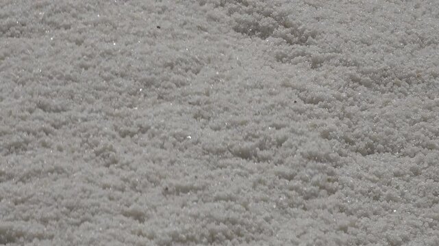 Abstract close-up shot of salt falling down on pile (as it drops from conveyor belt), in Chott El Djerid, agriculture and economy in Tunisia
