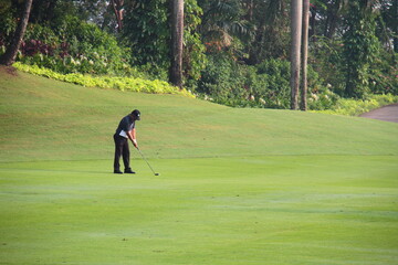 An Asian amateur golfer is getting ready to hit a golf ball