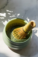 Matcha Preparation. A bamboo whisk in a bowl of frothy matcha,
