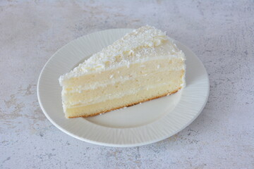 A slice of delicious coconut cake on a plate isolated
