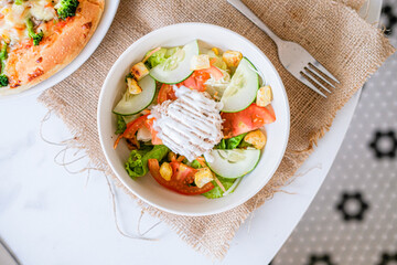
Fresh vibrant salad with crisp vegetables, croutons, and creamy dressing, accompanied by pizza and drinks, perfect for a healthy and hearty meal.
