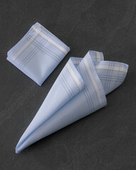 Folded blue handkerchiefs arranged on a dark background, showcasing classic men's accessories in a clean, elegant style.